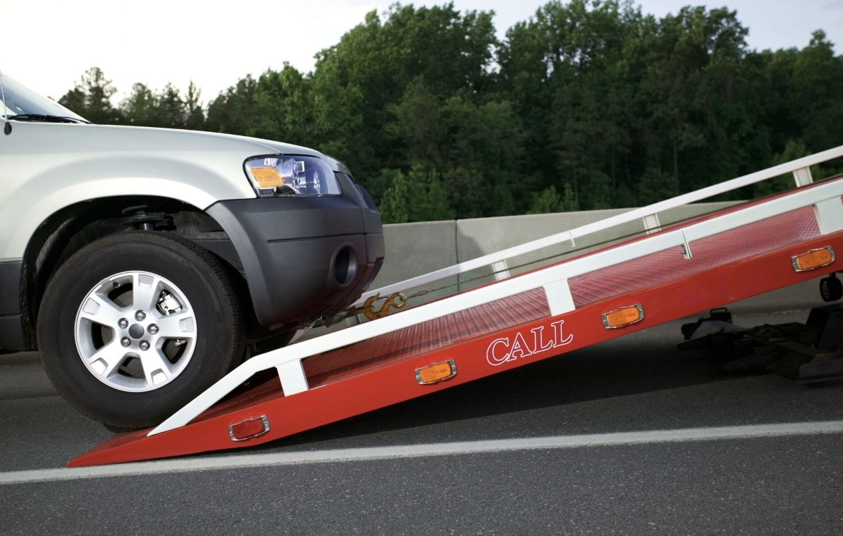 Flatbed tow truck ramp loading a vehicle for long distance towing near North Babylon, NY