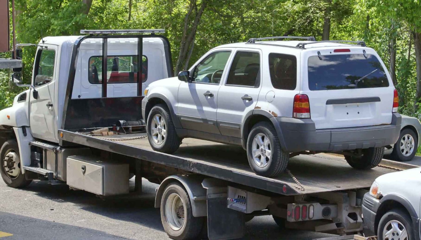 Flatbed tow truck transporting a vehicle safely on a street in North Babylon, NY